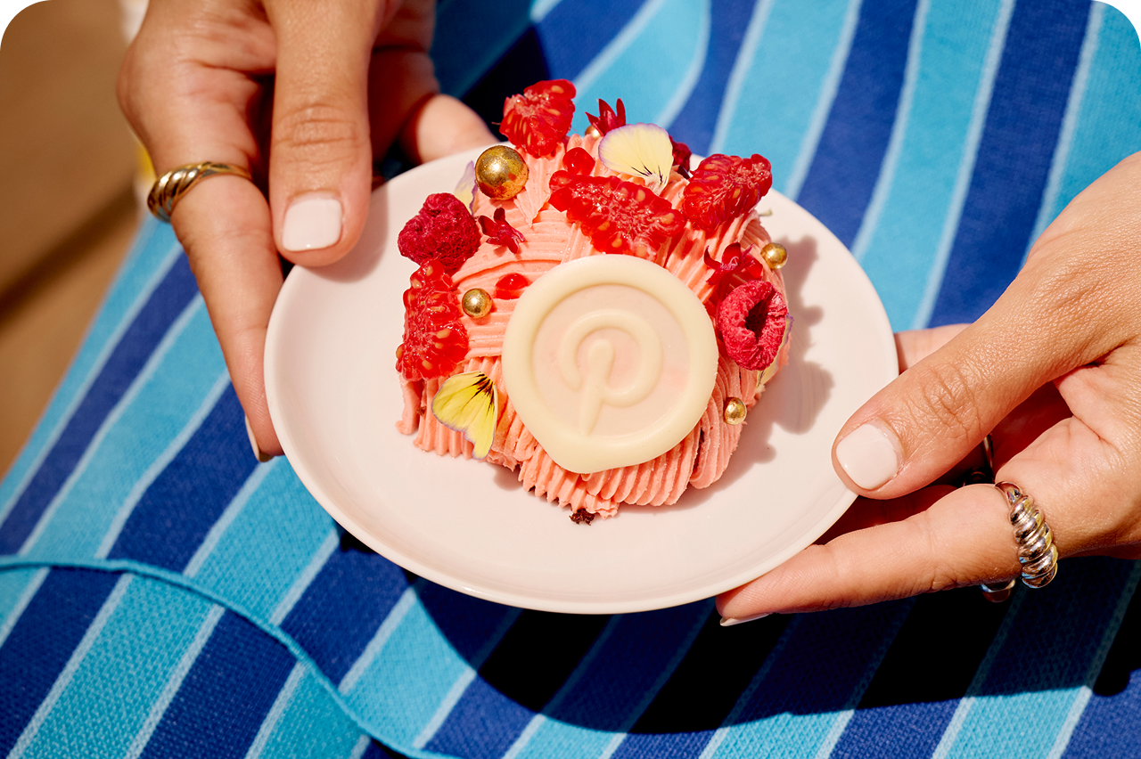 Hands presenting a plated dessert topped with raspberries